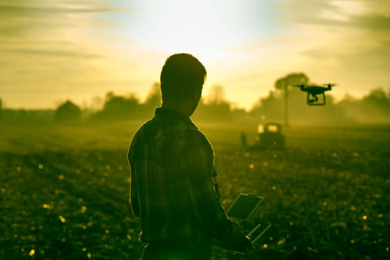 Farmer navigating drone above farmland